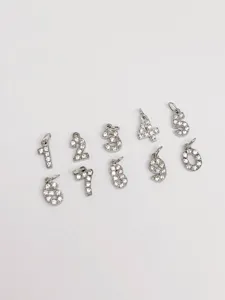Primo piano di ciondoli numerici in zircone pavé, dettagli in metallo argentato per gioielli DIY.