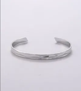 Minimalist stainless steel open cuff bracelet detail view showing hammered texture.