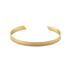 Close-up of minimalist gold-tone smooth open cuff bracelet detail showing sleek polished finish.