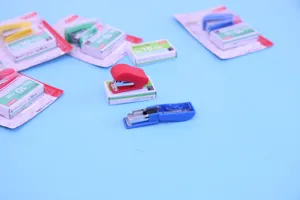 Kompakte Mini Tacker Detailansicht, mit bunten Schreibwaren und passenden Heftklammern.