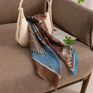 Detail shot of a retro blue and brown printed cashmere square scarf draped over a chic bag.