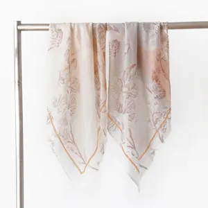 Close up detail view of lightweight printed cashmere square scarf hanging on metal rack, soft texture.