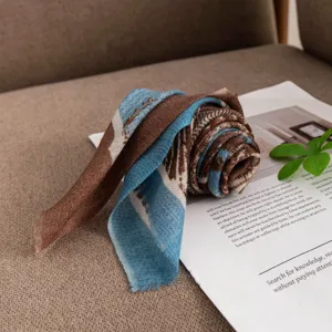 Detail view of a soft cashmere printed scarf rolled up with retro blue and brown patterns.