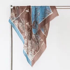 Detailed close-up of a vintage botanical print cashmere square scarf draped on a metal rack.
