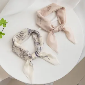 Detail view of two elegant women printed small square scarves, lightweight floral style.