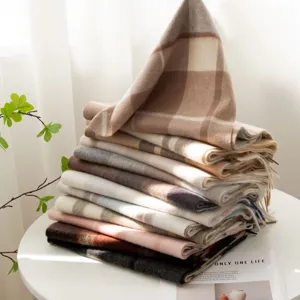 Detailed close-up view of stacked soft plaid cashmere scarves in warm neutral tones.