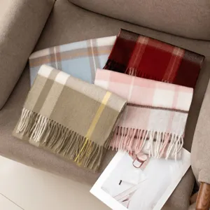 Detail shot of cozy cashmere-blend plaid scarves with fringe, displayed in warm tones.