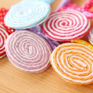 Close up detail of colorful spiral lollipop shaped decorative pen or craft item on wooden table.