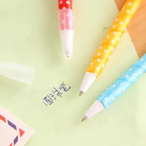 Close-up detail view of cute colorful polka dot ribbon ballpoint pens on stationery paper.
