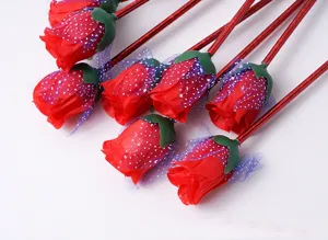 Close-up detail of artificial red rose flower ballpoint pens with green stems and sparkly mesh.