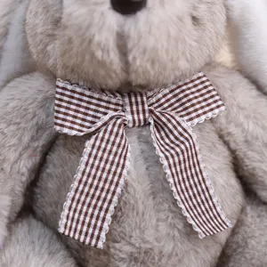 Gros plan détaillé de la peluche lapin douce avec un nœud papillon à carreaux marron.