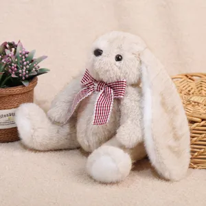 Adorable peluche de lapin aux longues oreilles assise avec nœud papillon écossais, doudou.