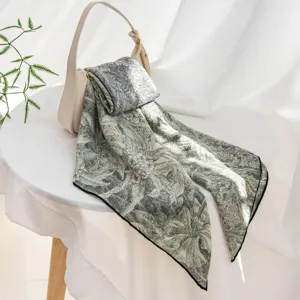 Vue détaillée d'un foulard imprimé floral botanique rétro drapé sur une table blanche.
