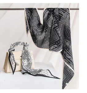 Detail view of a black and white silk paisley scarf styled gracefully with a chic handbag prop.