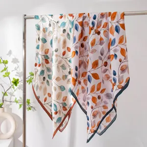 Detailed shot of mulberry silk square scarf with elegant botanical leaf watercolor print hanging.