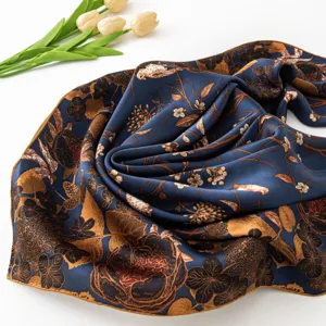 Close-up detail of a dark blue silk square scarf featuring elegant vintage floral and bird print.