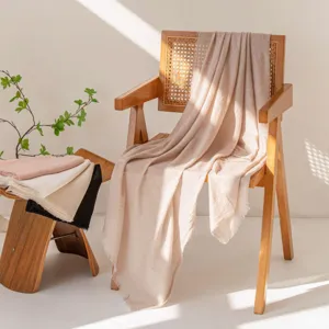 Vista dettagliata della sciarpa estiva beige leggera drappeggiata su mobili in legno.