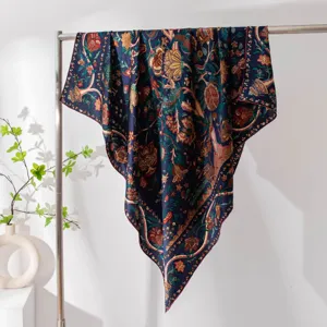 Detailed view of a dark blue silk square scarf with vintage floral prints draped on a metal rack.