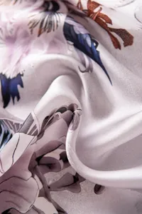 Detail shot of elegant silk square scarf with artistic abstract print and soft drape.