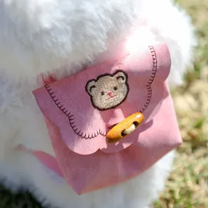 Nahaufnahme des weißen Plüschtier-Rucksacks mit besticktem Bären und Holzknopf.