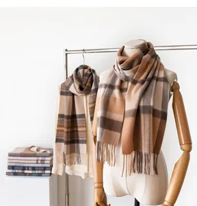 Detail view of a classic winter plaid scarf featuring a stylish camel brown fringe design