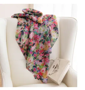 Detailed shot of a vintage floral silk scarf draped over a white chair with a chic bag.