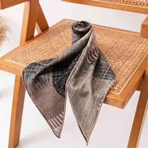 Primo piano di un foulard triangolare in seta e lana con stampa geometrica su sedia retrò.