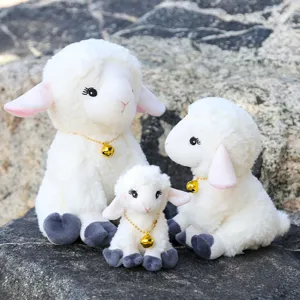 Detail shot of cute sitting plush sheep toys with golden bells on natural rock background.