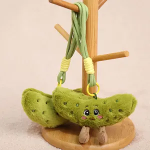 Close-up detail of the green pickle plush toy keychain showing soft texture and cute embroidered face.