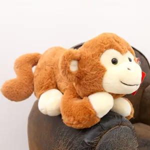 Simpatica scimmia di peluche marrone in posizione sdraiata bambola morbida regalo per bambini.