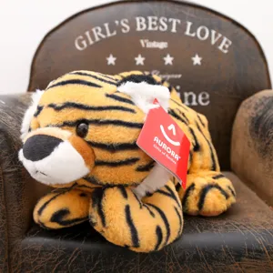 Primo piano di un simpatico peluche di tigre sdraiato con etichetta rossa su sedia.