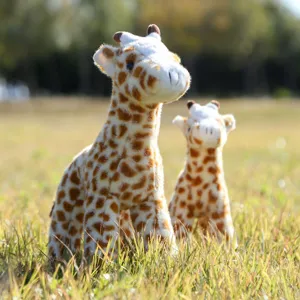Detailed shot of cute standing plush giraffe toy in outdoor grassy field setting scene.