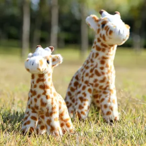 Detailed shot of cute stuffed giraffe plush toys sitting on green grass outdoors, soft toy.