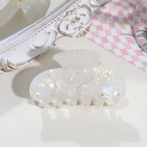 Detail view of the iridescent white acetate angel wing hair claw with rhinestone details.