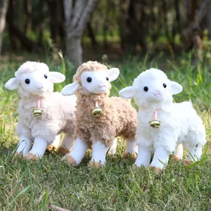 Detailed view of cute standing plush sheep toys with bells in a natural outdoor grass scene.