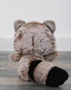 Detaillierte Rückansicht eines niedlichen Plüsch-Waschbären auf einem schönen Holztisch.