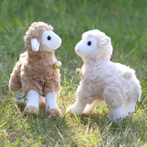 Close up of cute standing sheep plush toys with bells on grass background for sweet detail display.