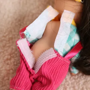 Close-up detail of mini doll clothes, pink corduroy overalls and plaid top with velcro.