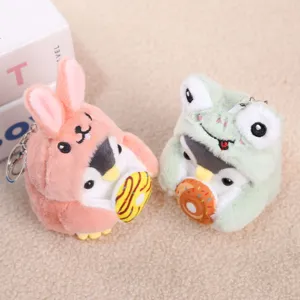 Primo piano dettagliato di simpatici portachiavi pinguino di peluche vestiti da coniglio e rana.