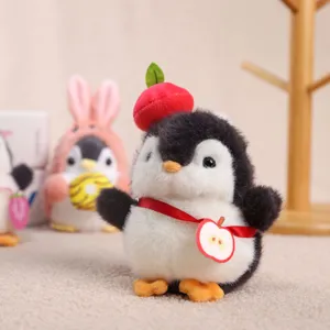 Primo piano dettagliato di simpatico giocattolo pinguino di peluche con cappello di mela rossa.