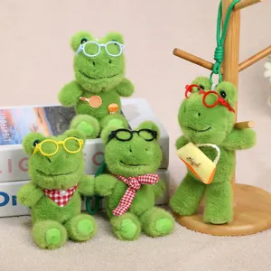 Vista detallada de llavero de peluche de rana verde, animal de peluche suave con gafas y accesorios.