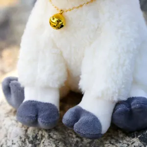 Close-up detail of cute sitting sheep plush toy with golden bell necklace and soft fleece.