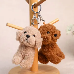Close-up detail of cute plush teddy dog keychains, fluffy puppy pendants on wooden stand.