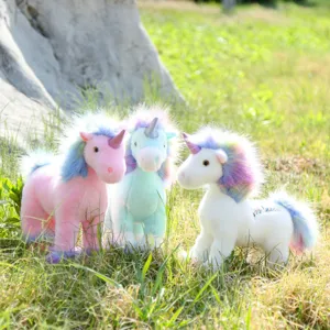 Detailed view of cute standing rainbow unicorn plush toys in a scenic outdoor grass setting.