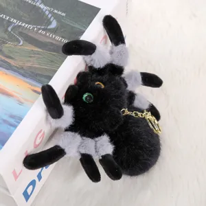 Detailed close-up of a fluffy black and grey plush spider keychain with big eyes and a gold chain.