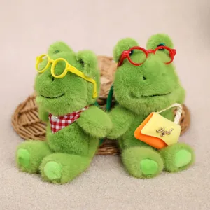 Primer plano de lindo llavero de felpa de rana verde con gafas y bolso pequeño.