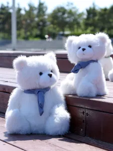 Dettaglio in primo piano di simpatici orsacchiotti di peluche bianchi con sciarpe in maglia blu.