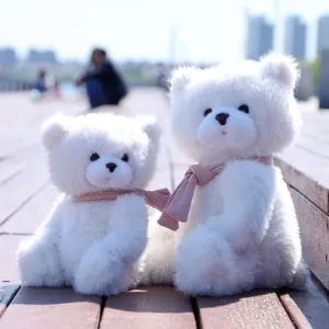 Primo piano dettagliato di simpatici orsacchiotti di peluche bianchi con sciarpe rosa.