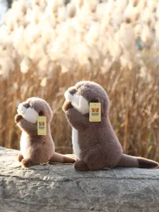 Detailed shot of cute praying otter plush toys sitting on a rock with natural reed background.