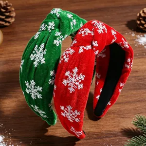 Dettaglio della fascia per capelli in velluto natalizio con fiocchi di neve paillettes.